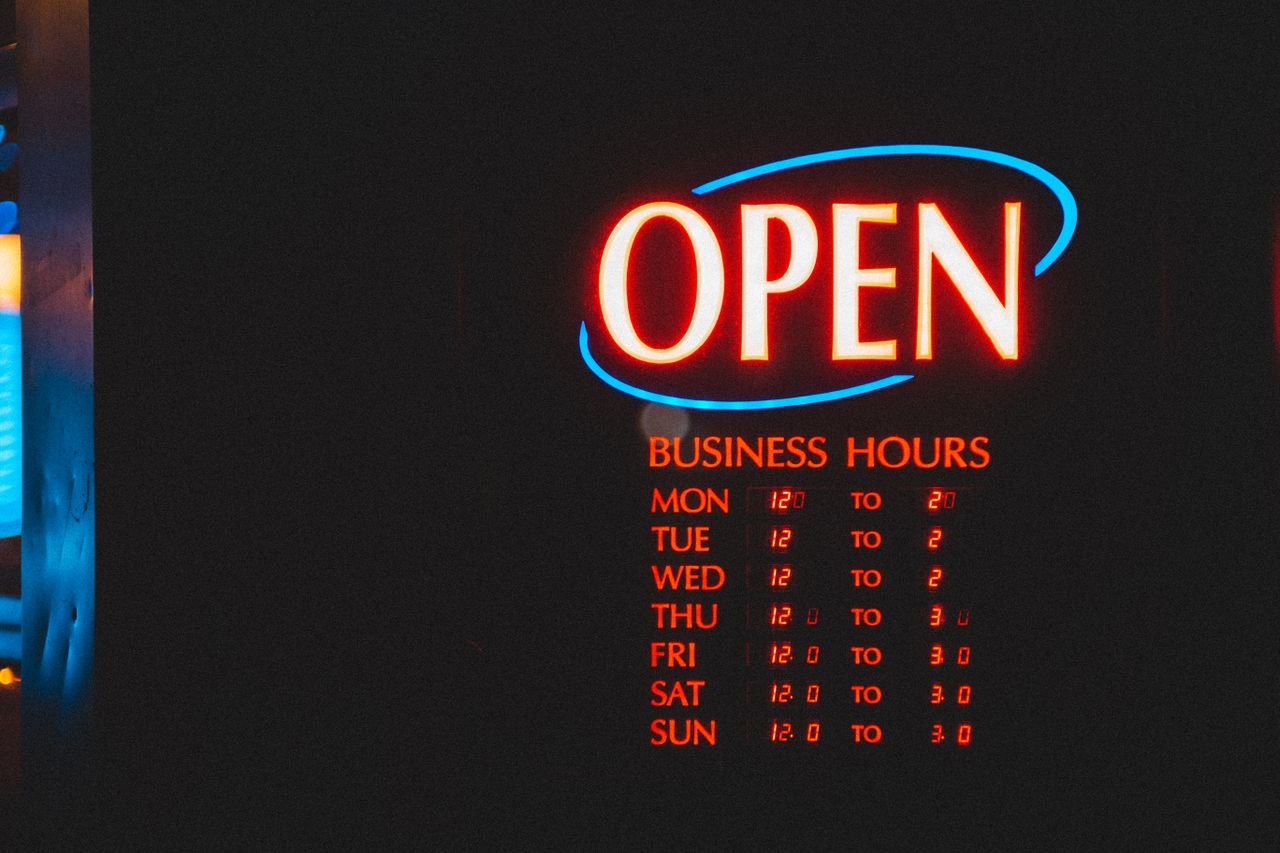 why-choose-us LED open sign with glowing business hours and flashing effects depicted on black board on street in city on evening time